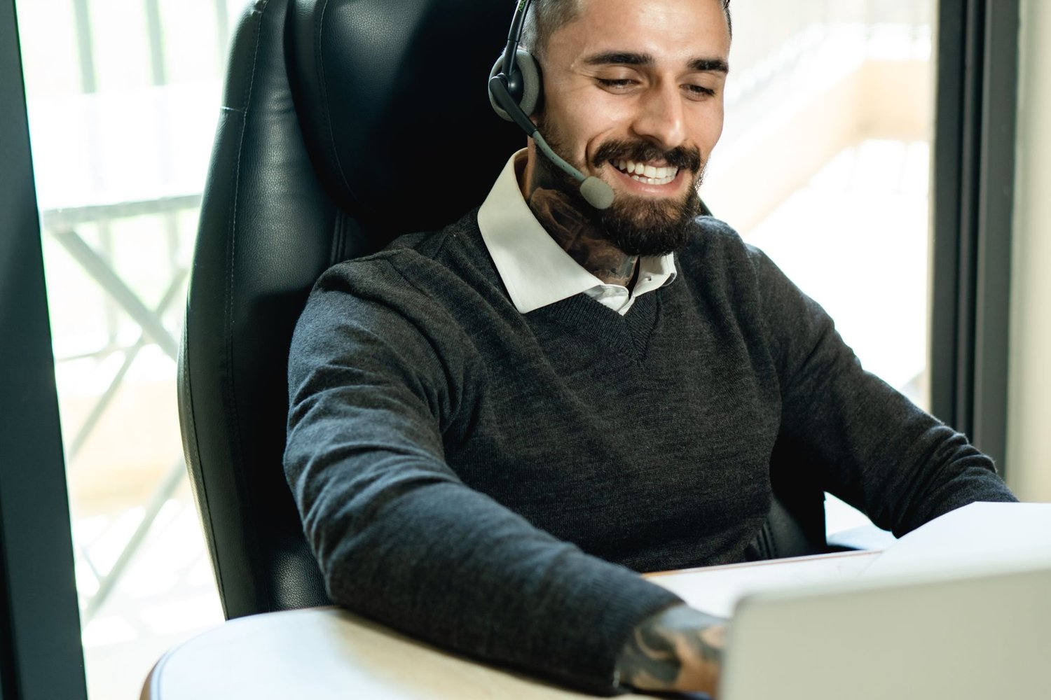Professional wearing a headset answering a call at a desk in warm light