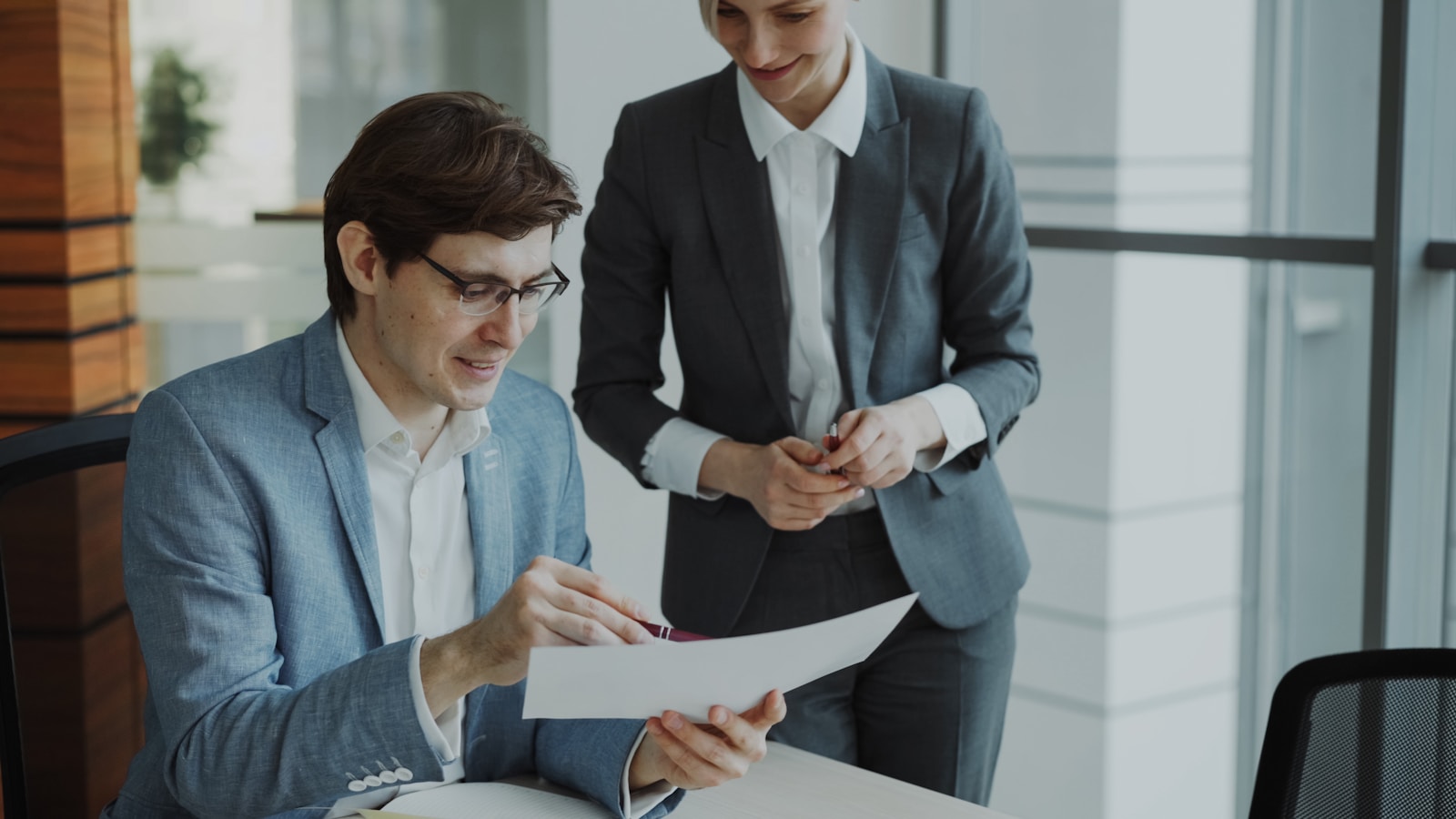 Two professionals reviewing reports together while deciding whether to hire a legal-specific marketing agency
