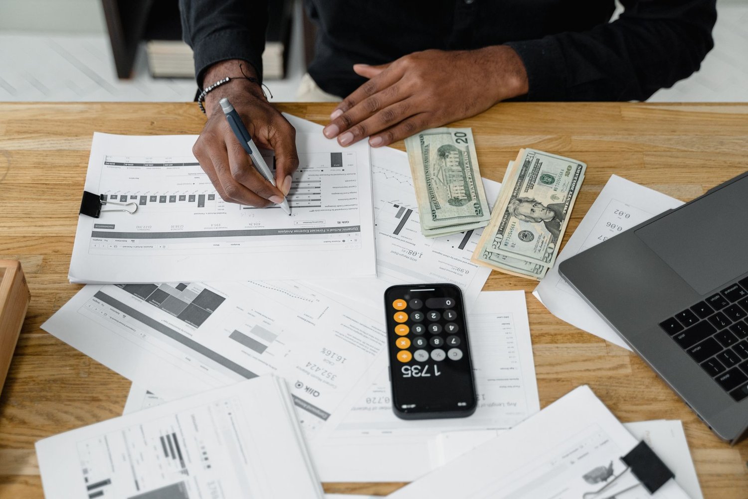 Hands reviewing printed marketing performance reports with a calculator on a desk