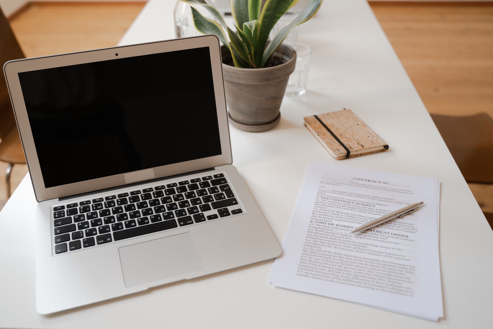 A printed contract and a closed laptop on a bright desk, illustrating a law firm reading the fine print of an advertising policy before buying a new ad channel.